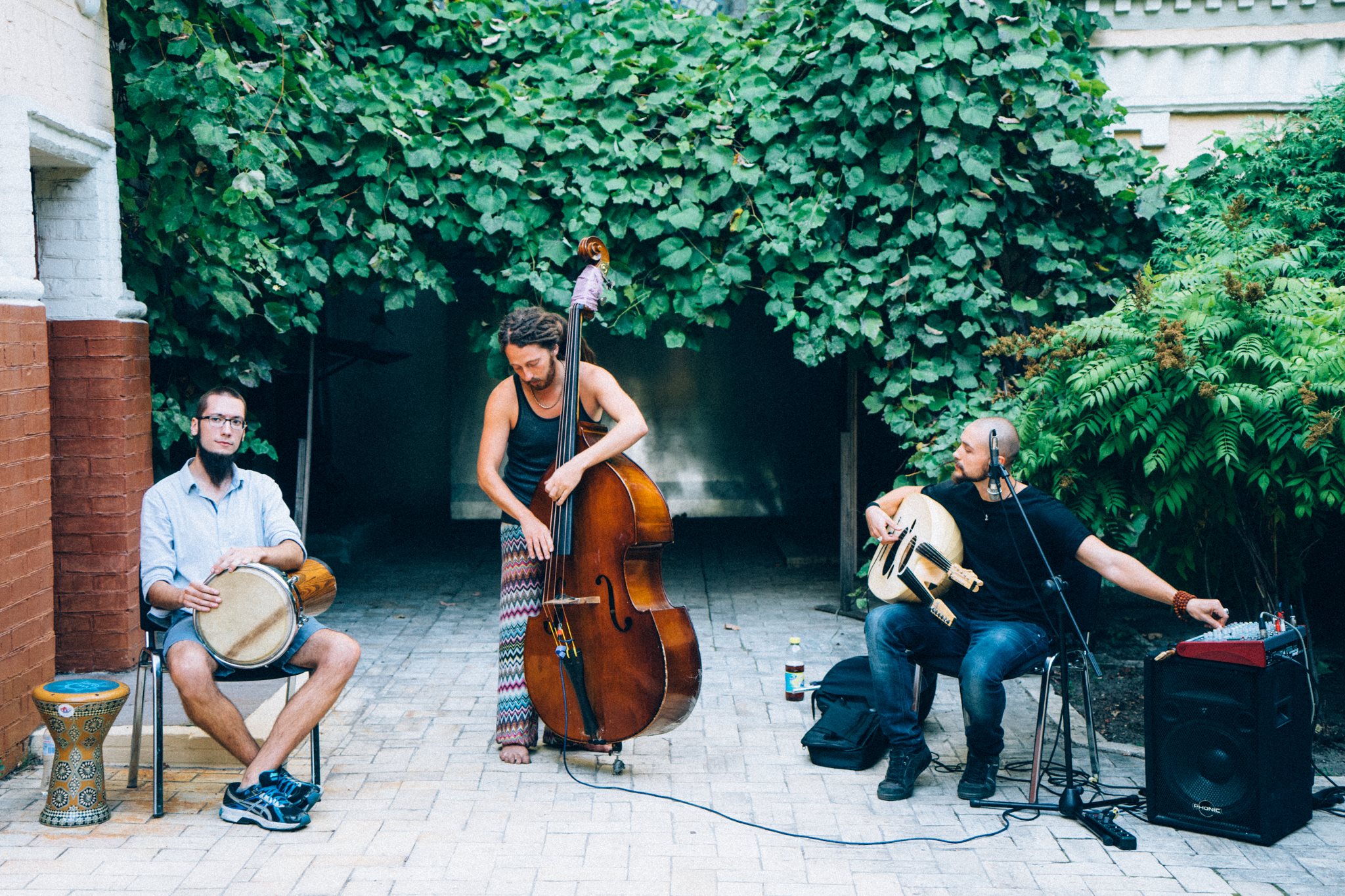 Фото. Троє музикантів виступають на концерті в музейному дворику влітку