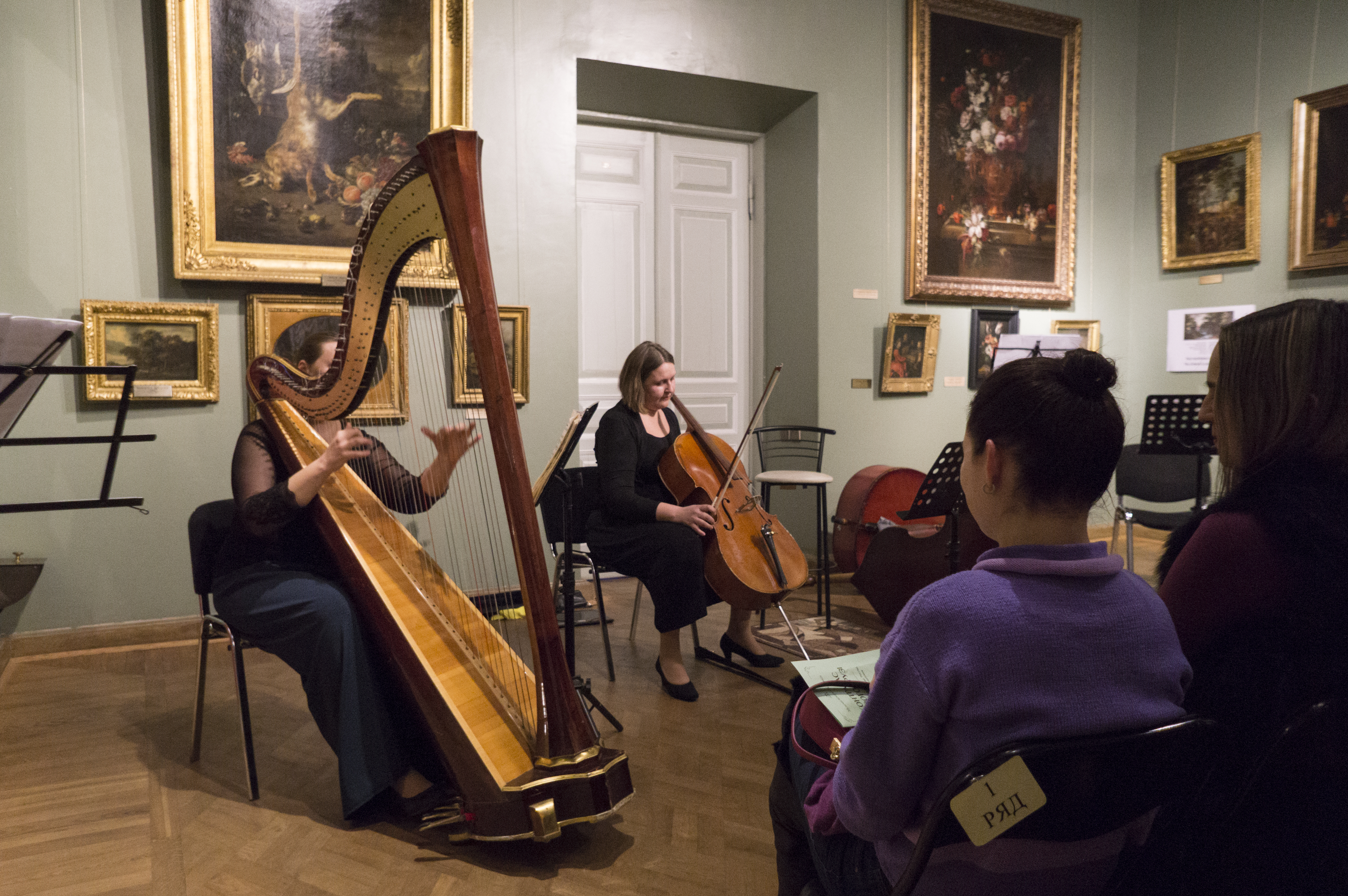 Фото. Концерт класичної музики в залі музею (жінки грають на арфі та віолончелі)