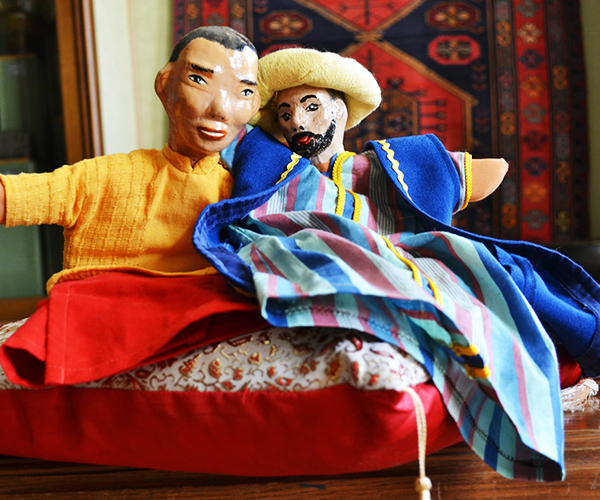 Photo. Two apier-mache puppets on the pillow in the middle of the museum hall